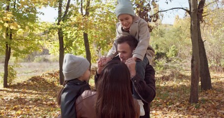 Family, children, parents walk in autumn park. They play and laugh together among golden leaves in nature. Soft sunlight and relaxed stroll create happiness. Happy childhood and family togetherness. - Powered by Adobe