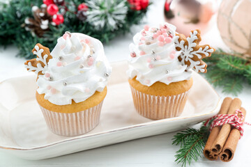 Tasty cupcakes with Christmas decor and cinnamon on white wooden table, closeup