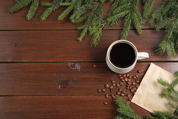 Aromatic coffee in cup, beans and fir tree branches on wooden table, flat lay. Space for text