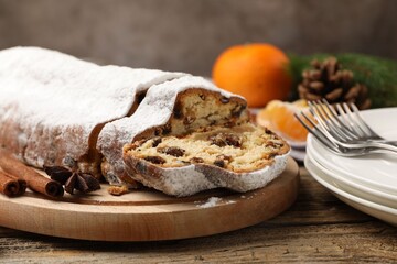 Traditional Christmas Stollen with icing sugar, spices, tangerine and festive decor on wooden table, closeup