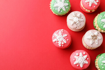 Beautifully decorated Christmas macarons on red background, flat lay. Space for text