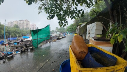 A Close-Up View of Wet, Old Yellow Plastic Crates and Blue Baskets During a Cloudy, Overcast Rainy Day in a Tropical City