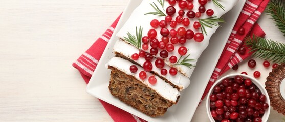Tasty Christmas cake with icing, cranberries, rosemary and festive decor on white wooden table, flat lay. Space for text
