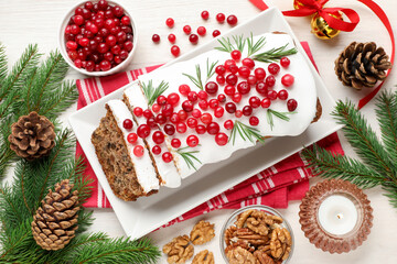 Tasty Christmas cake with icing, cranberries, rosemary and festive decor on white wooden table, flat lay