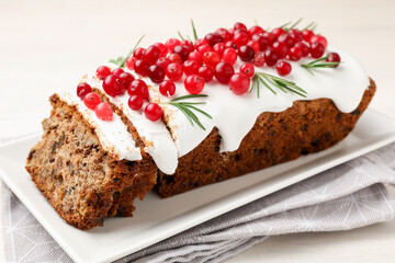 Tasty Christmas cake with icing, cranberries and rosemary on white wooden table, closeup