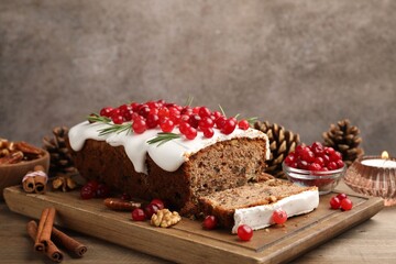 Tasty Christmas cake with icing, cranberries and rosemary on wooden table, closeup