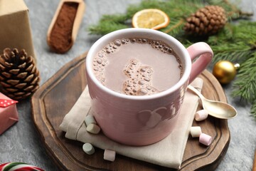Tasty cocoa, marshmallows and Christmas decor on grey table, closeup