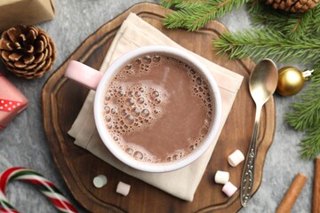 Tasty cocoa, marshmallows, cinnamon, candy cane and Christmas decor on grey table, flat lay
