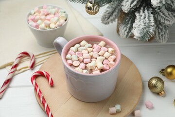 Tasty cocoa with marshmallows and Christmas decor on white wooden table, closeup