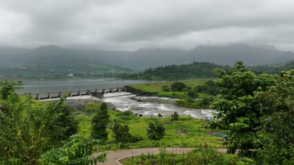Scenic View of Dam with Overflowing Water During Monsoon Season in Lush Green Landscape
