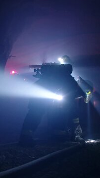 Rescue forces search for survivors inside a dark tunnel using flashlights