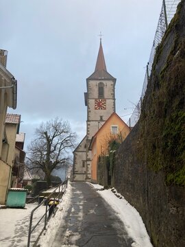 Winterlicher Aufstieg zur Stadtkirche in Sulz am Neckar mit schneebedecktem Weg, historischem Kirchturm und ruhiger Kleinstadtatmosph&auml;re
