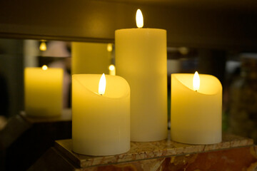Fausses grosses bougies allumées en décoration dans un intérieur, se reflétant dans un miroir