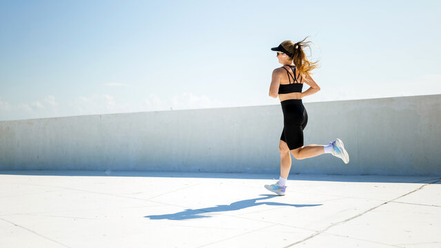 Woman jogging on a rooftop under clear sky