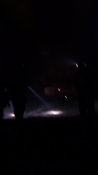 Rescue forces search for survivors inside a dark tunnel using flashlights