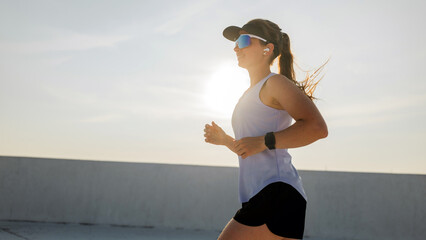 Woman jogging outdoors in activewear with earbuds