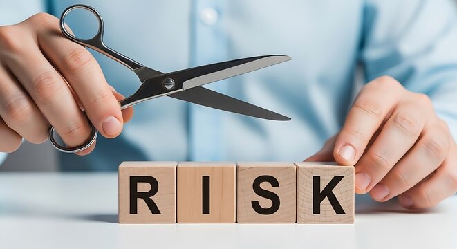 Person cutting the word risk with scissors, symbolizing risk reduction and management