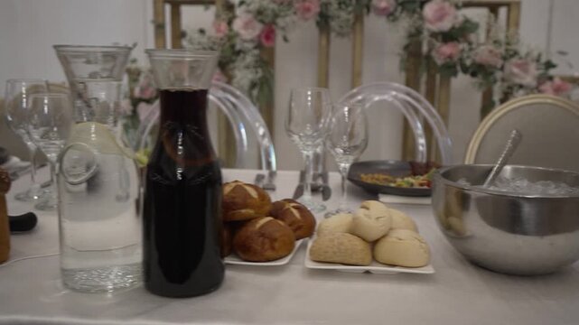 A festive table setting featuring traditional challah bread, water, and juice. The elegant scene evokes a celebratory mood, perfect for Jewish holidays, weddings, or family events.