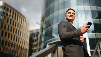 Man in suit smiling with phone in urban setting