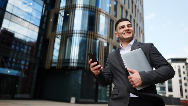 Smiling businessman with laptop outdoors