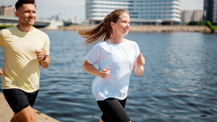 Couple jogging along the riverside in the city