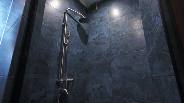 Luxury shower with dark blue marble tiles and a modern chrome fixture. A sleek linear drain and glass enclosure complete this sophisticated, spa-like space