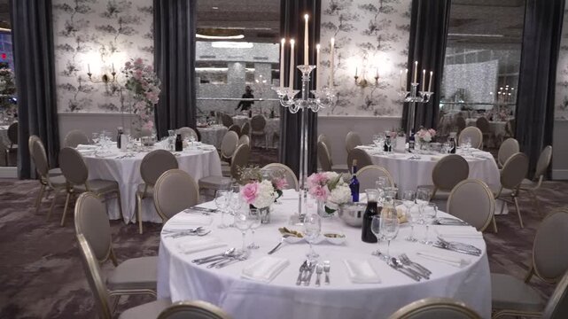 An elegantly decorated banquet hall with tables set for a formal dinner. The romantic and luxurious atmosphere is perfect for a special occasion. Use for wedding or event planning content.