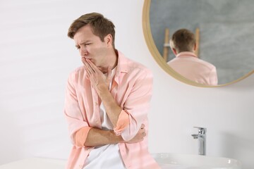 Fototapeta premium Young man suffering from nausea and stomachache in bathroom