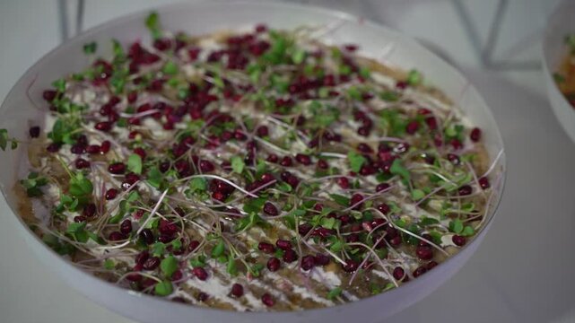 A delicious Middle Eastern dip, possibly baba ghanoush, garnished with pomegranate and microgreens. This fresh, healthy, and gourmet appetizer is perfect for food blogs or menus.