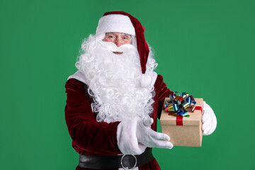 Santa Claus with Christmas gift on green background
