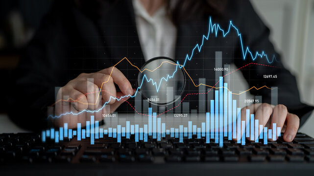 A business analyst uses a magnifying glass to examine financial trends with digital graphs and charts on a keyboard, showcasing insights into market analysis. Scalp