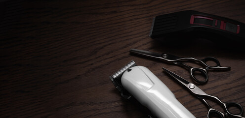 Hairdressing and barber tools. Professional scissors and hairdressing clippers. Dark wooden background.