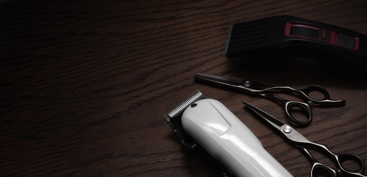 Hairdressing and barber tools. Professional scissors and hairdressing clippers. Dark wooden background.