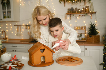 A mother and son are preparing a gingerbread house for the Christmas and New Year holidays.