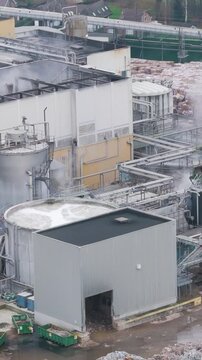 industrial plant factory during daylight oudegem belgium recycling paper operations steam rising from industry aerial drone panning shot vpk packaging group view 