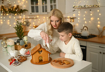 A mother and son are preparing a gingerbread house for the Christmas and New Year holidays.