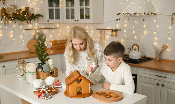 A mother and son are preparing a gingerbread house for the Christmas and New Year holidays. - Powered by Adobe