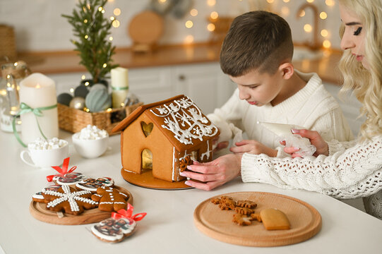 A mother and son are preparing a gingerbread house for the Christmas and New Year holidays.
