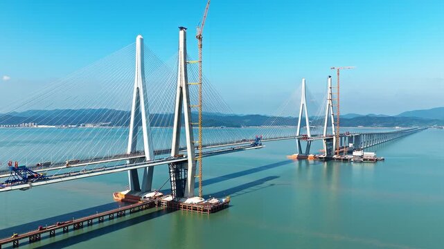Aerial shot of a massive cable-stayed bridge under construction, an impressive feat of engineering and infrastructure over the sea. Famous Xiangshan Port Cross-Sea Bridge is located in Ningbo, China.