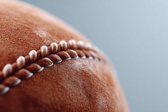 Extreme closeup of a textured, brown sports ball with white stitching. Captures detail and craftsmanship, perfect for sports, teamwork, and game day themes. - Powered by Adobe