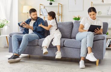 Child girl seeks attention as parents use smartphone. At home, the mother and father focus on...