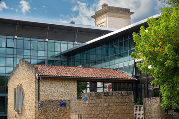 Mont de Marsan showcases a blend of old and new architecture. The historic stone building contrasts with the sleek glass structure, reflecting the area's rich history and modern development.