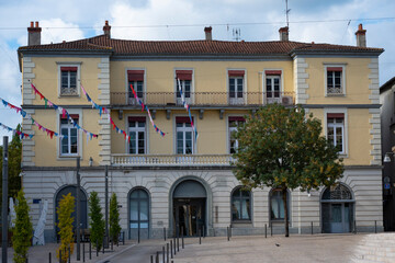 A historic yellow building in Mont de Marsan displays colorful decorations. The scene captures the inviting atmosphere, with clear skies and decorative flags adorning the facade.