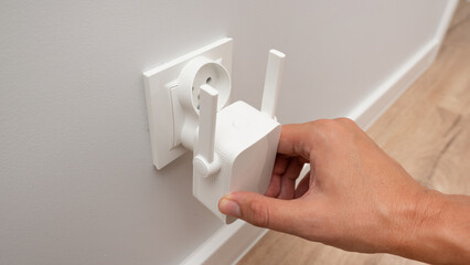 Wireless Wi-Fi repeater on white wall indoors