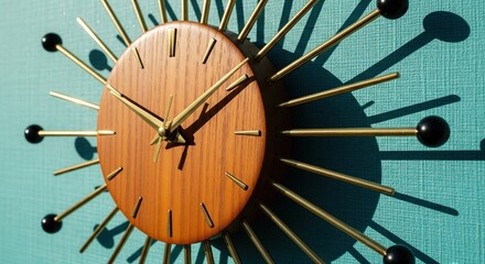 Mid century modern sunburst wall clock with wood and brass on a turquoise wall casting shadows