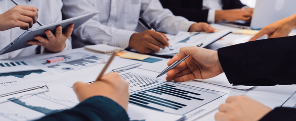 A diverse team engages in a collaborative business meeting, surrounded by charts and digital devices, focusing on strategic planning and performance analysis for effective growth. SACTR