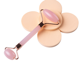 Pink Gua Sha massage tool on a white background, close-up. Rose Quartz jade roller.