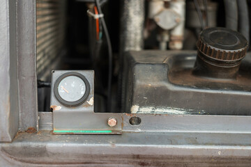 An analog fuel level gauge of the electricity generator machine. Industrial equipment object, close-up.