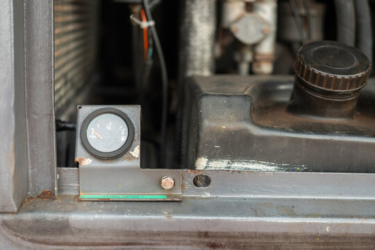 An analog fuel level gauge of the electricity generator machine. Industrial equipment object, close-up.