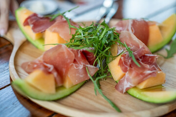 Fresh Melon and Prosciutto Appetizer on Wooden Plate